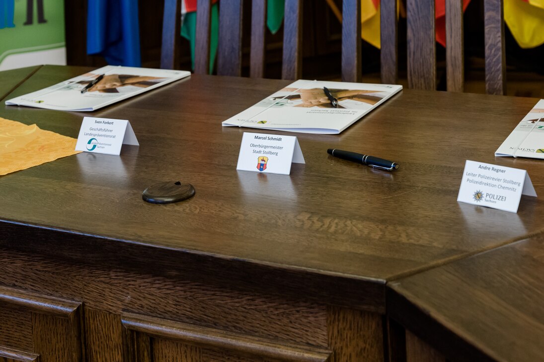 Die Kooperationsvereinbarung liegt auf dem Tisch. Davor stehen Tischkarten mit den Namen der Personen, welche unterzeichnen. 