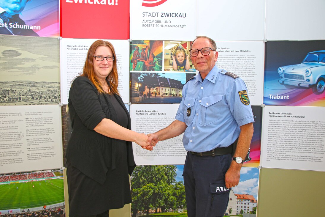 Zwei Teilnehmer der Sitzung stehen vor der "Zwickau Wand" und reichen sich die Hand.