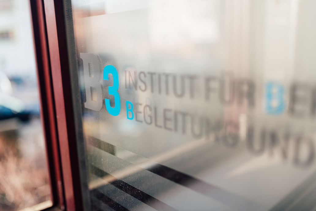 Schriftzug des Institutes B3 e. V. in blauer Schrift auf einem Fenster.