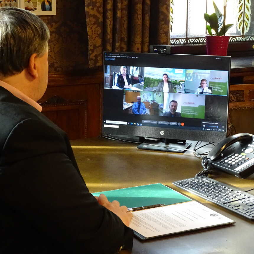 Auf einem Computerbildschirm sieht man die Teilnehmer der Videokonferenz und der Oberbürgermeister von Werdau sitzt vor dem Bildschirm an seinem Schreibtisch.