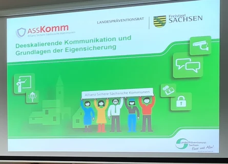 Präsentation des Vortragen von Torsten Kosuch zum Thema Gewalt und dessen Umgang beim Seminar Deeskalationstraining. Man sieht eine digitale Leinwand mit einer grünen Folie auf der das typische ASSKomm Logo zu sehen ist und dann das Thema des Vortrages