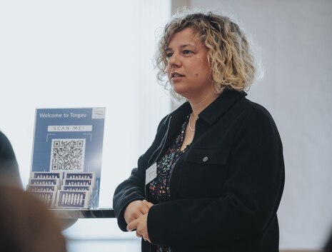 Julia Klöppel steht an ein Pult gelehnt und spricht.