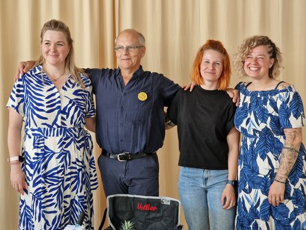Volker Pfitzner wird umringt von drei Frauen und strahlt in die Kamera.