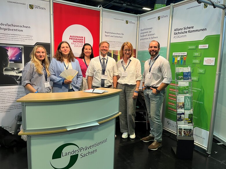 Sechs Personen stehen im Messestand des Landespräventionsrates. Im Vordergrund steht ein Counter.