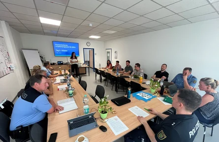 Die Workshopteilnehmer sitzen an Tischen und schauen zur Referentin, die vorn steht.