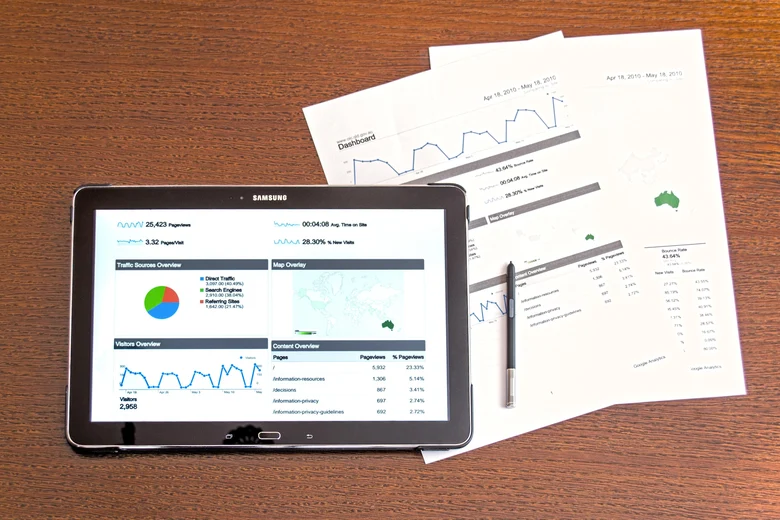 Ein Laptop zeigt Tabellen und Diagramme. Daneben liegen auch noch Ausdrucke mit Diagrammen.