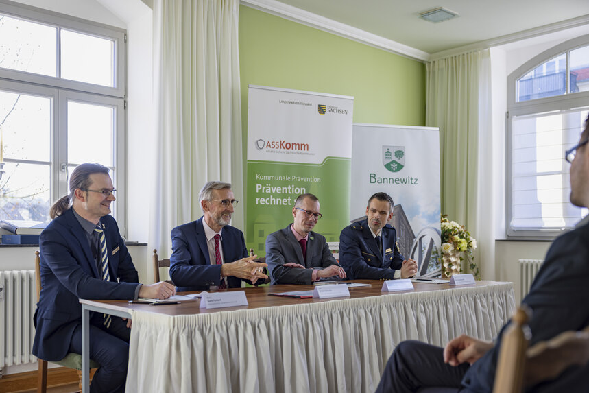 zeigt Sven Forkert, Innenminister Armin Schuster, Bürgermeister Heiko Wersig sowie Polizeirat Martin Gebhardt an einem Tisch sitzend