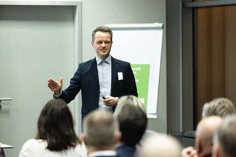 Markus Mehnert steht vor einem Flipchart vor den Teilnehmenden, die man von hinten sieht.