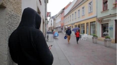 Ein Mann steht in einem Hauseingang und wartet auf Opfer.