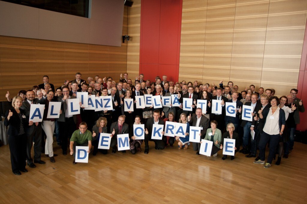 Große gruppe von Personen welche Buchstaben Schilder mit der Aufschrift: Allianz Vielfältige Demokratie hochhalten