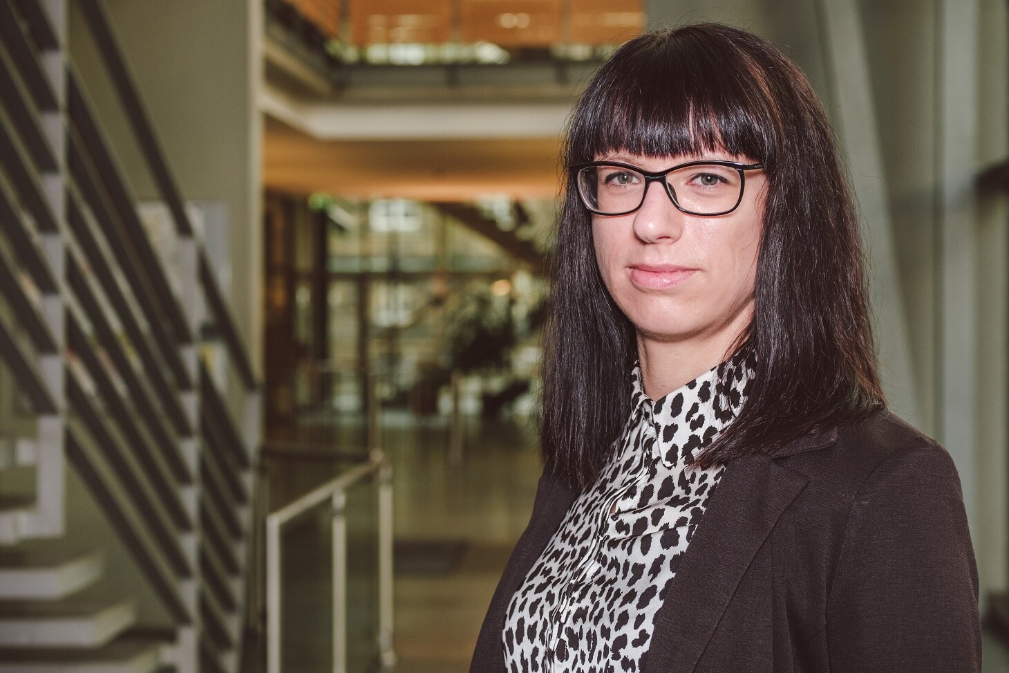 Anja Herold-Beckmann im Portrait, im Foyer des SMI, sie trägt ein schwarzes Jacket mit einer weiß-schwarzen Bluse.