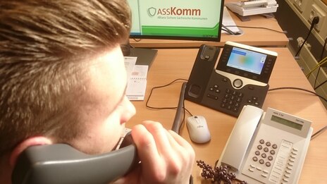 Ein junger Mann telefoniert von seinem Arbeitsplatz aus. 