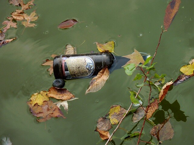 zeigt eine Bierflasche im Wasser schwimmend