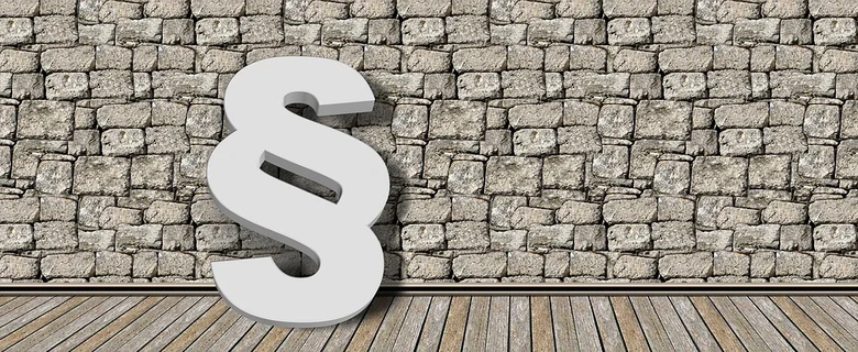 ein weißes Paragraph Zeichen vor einer grauen Steinwand