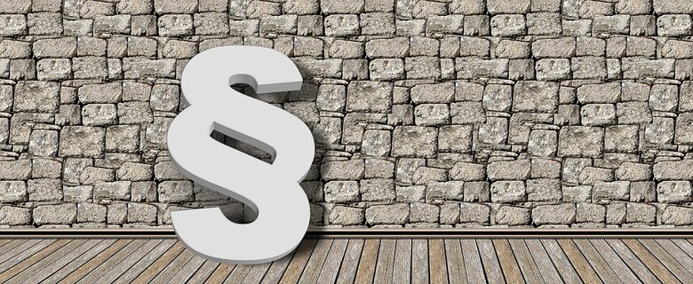 ein weißes Paragraph Zeichen vor einer grauen Steinwand