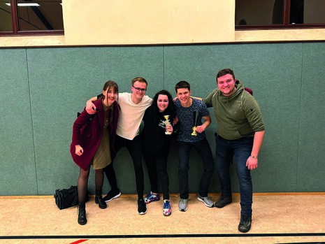 Auf dem Bild sieht man 5 junge Menschen vor einer Wand.