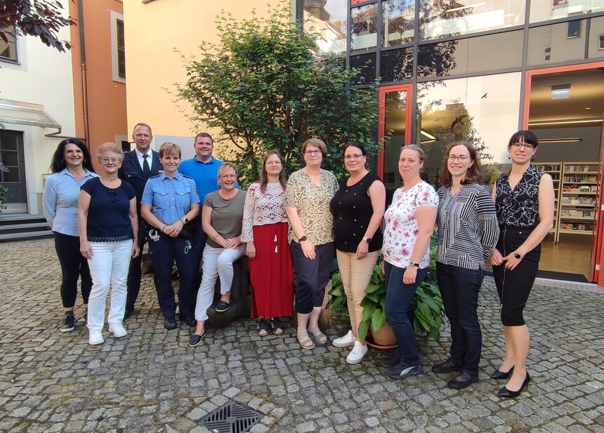 12 Personen stehen und schauen zum Fotografen.