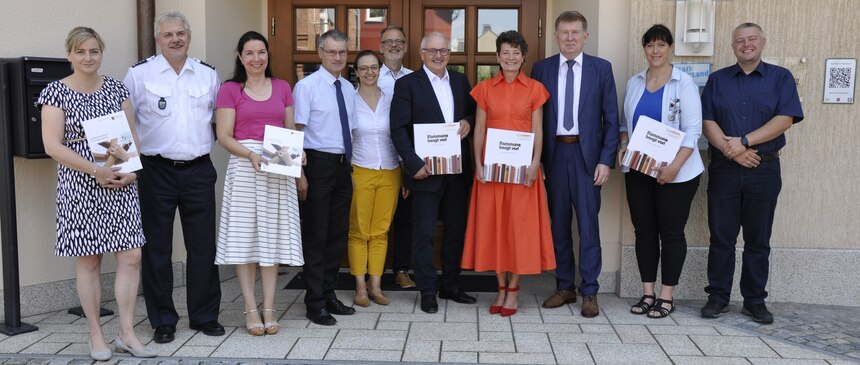 Alle Teilnehmer an der Unterzeichnung der Kooperationsveranstaltung stehen vor dem Rodewischer Rathaus. Die Unterzeichner halten ein Buch bzw. eine LPR-Mappe in den Händen.