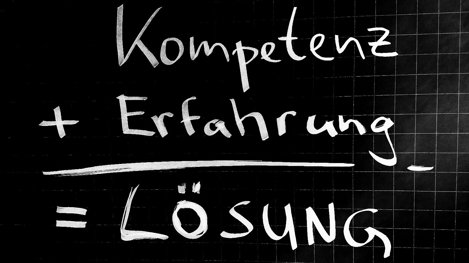 Schwarze Tafel mit der Schrift Kompetenz + Erfahrung = Lösung