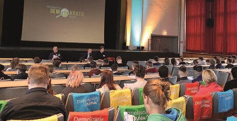 Auf dem Bild sieht man viele Personen in einer Stadthalle.