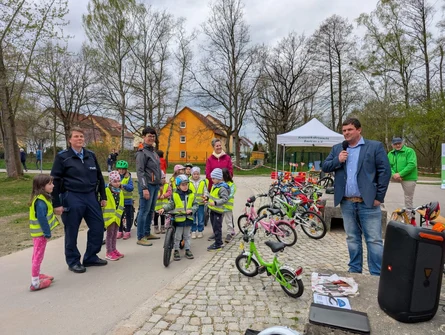 OB Höhme steht am Mikrofon und eröffnet die Veranstaltung. Neben ihm stehen einige Kinder und drei Erwachsene.