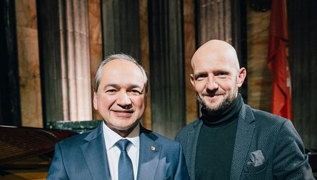 Portraitbilder von zwei Männern vor einem dunklen Hintergrund.