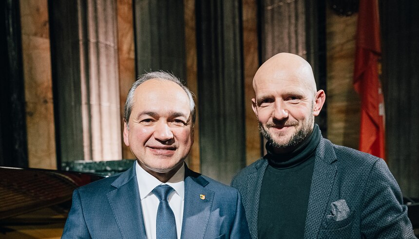 Portraitbilder von zwei Männern vor einem dunklen Hintergrund.