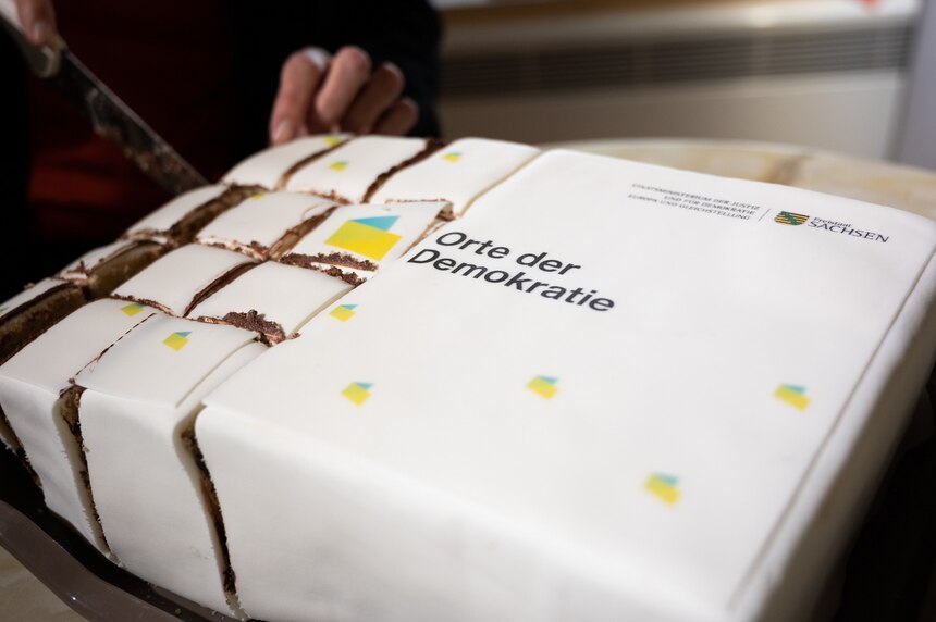 Torte mit Zuckerguss überzogen bereits eine Hälfte in Stücke geteilt und auf der anderen Seite steht Orte für Demokratie