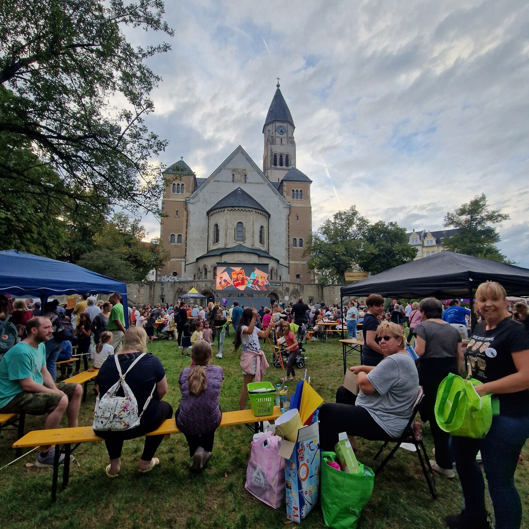 Im Hintergrund steht die Kirche, davor die Filmleinwand. Im Vordergrund sitzt das Publikum.