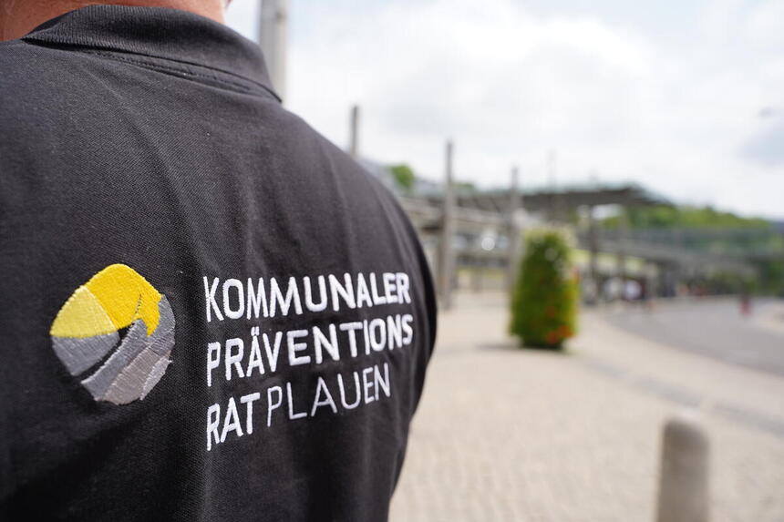 Rückseite einer Person welche ein schwarzes T-Shirt mit der Aufschrift: Kommunaler Präventionsrat Plauen trägt