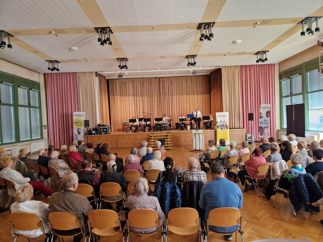 Auf der Bühne sitzt die Dixielandformation des Polizeiorchesters Sachsen und davor die Zuschauer.