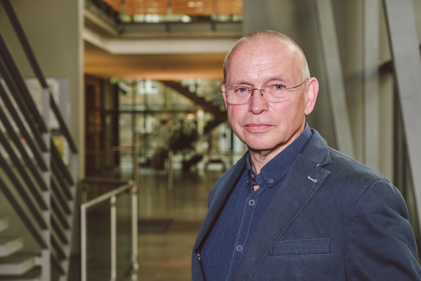 Torsten Kosuch im Portrait, im Foyer des SMI, er trägt ein blaues Jacket mit einem blauen Hemd.