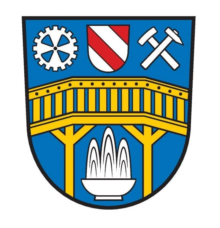 Wappen der Stadt mit gelber Brücke, einem Zahnrad, Hammer und Meisel und anderen Symbolen