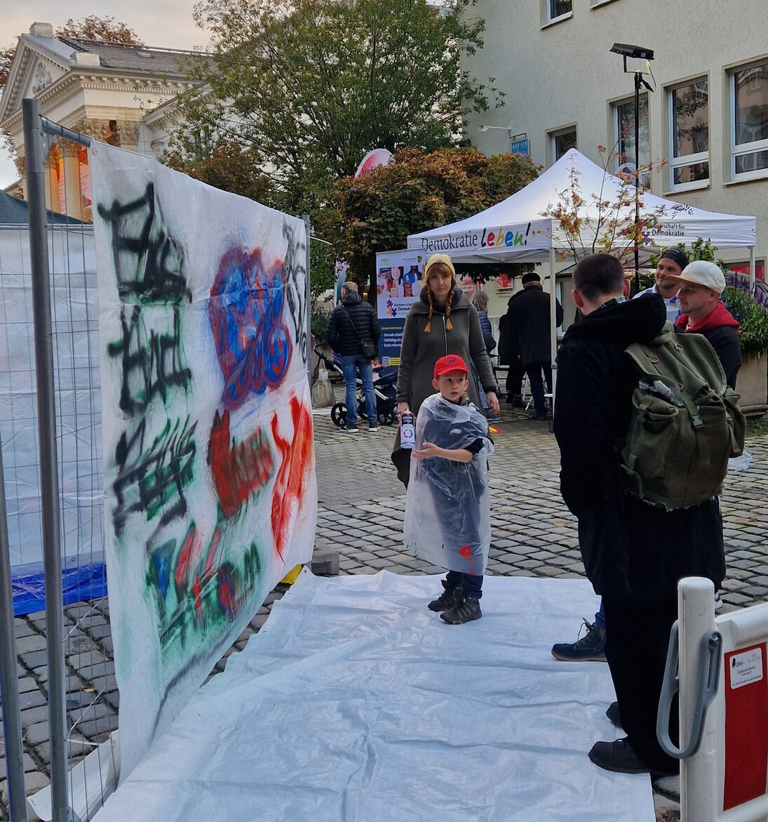 Es sind verschiedene Stände zu sehen und ein kleiner Junge der sprayt.